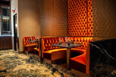 Tycoon Flower Mound- upscale restaurant and bar with golden tones, red velvet rounded booths and tufted wall
